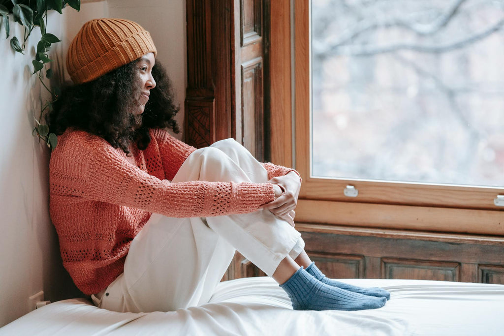 Woman sitting by a window in a cozy Christmas outfit