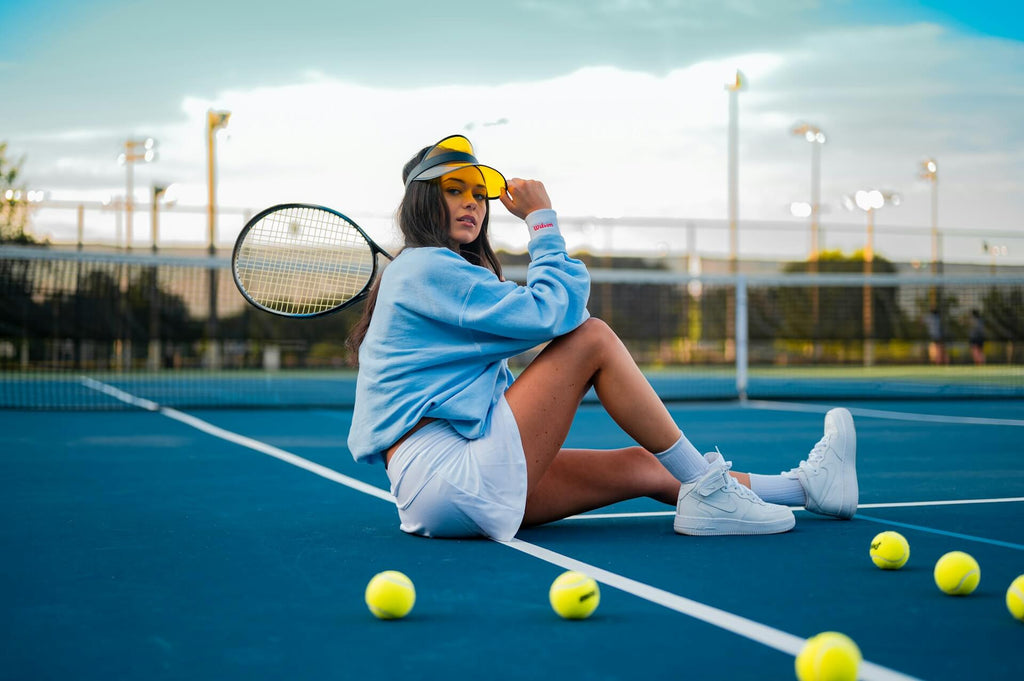Woman in elevated athleisure outfit sitting on a tennis court