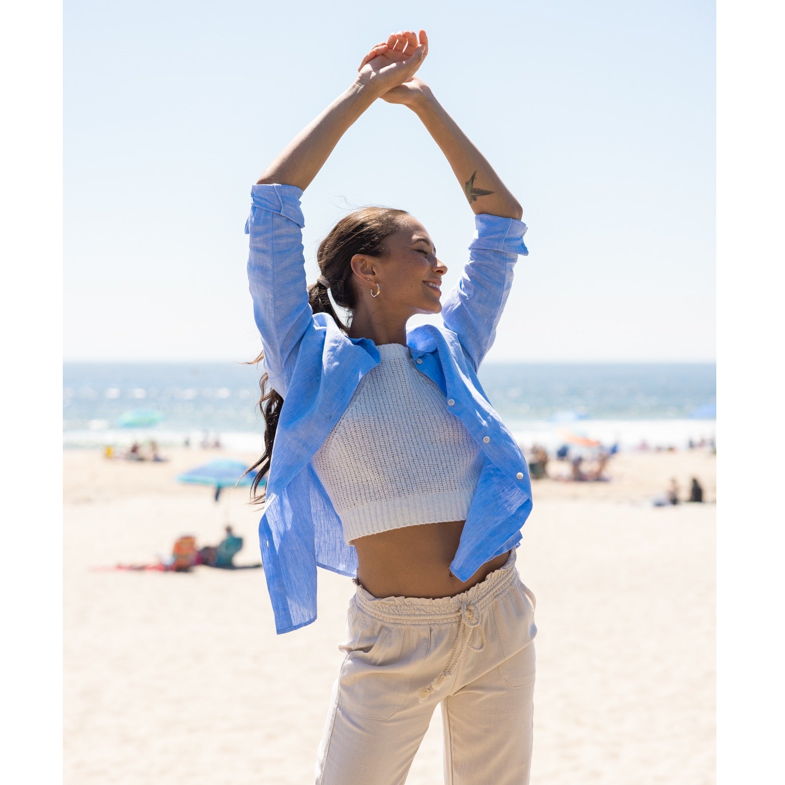 a woman wearing a blue linen shirt on the beach