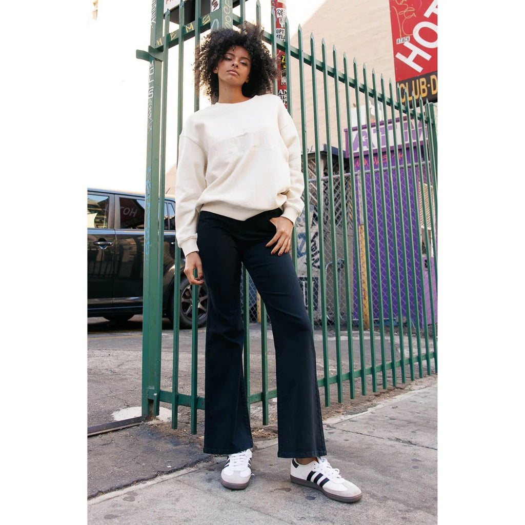 Woman in black high-rise flare jeans & a cream sweatshirt