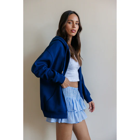 Woman in a blue hoodie layered over a white tee and mini skirt
