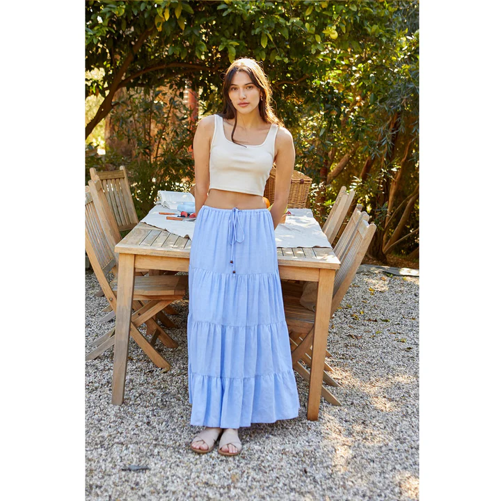 Woman wearing a blue linen maxi skirt with a white crop top