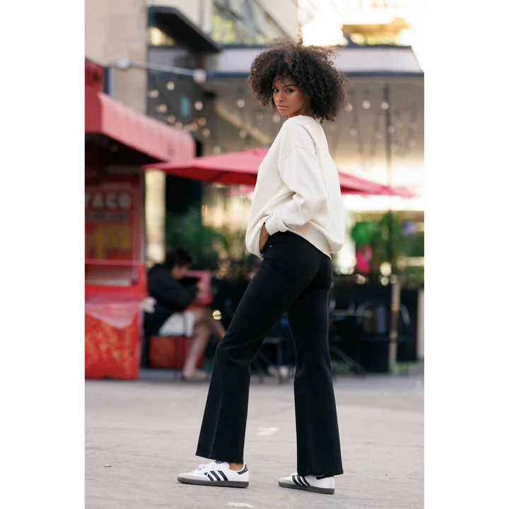 A woman wearing classic flare jeans in black with a white sweatshirt