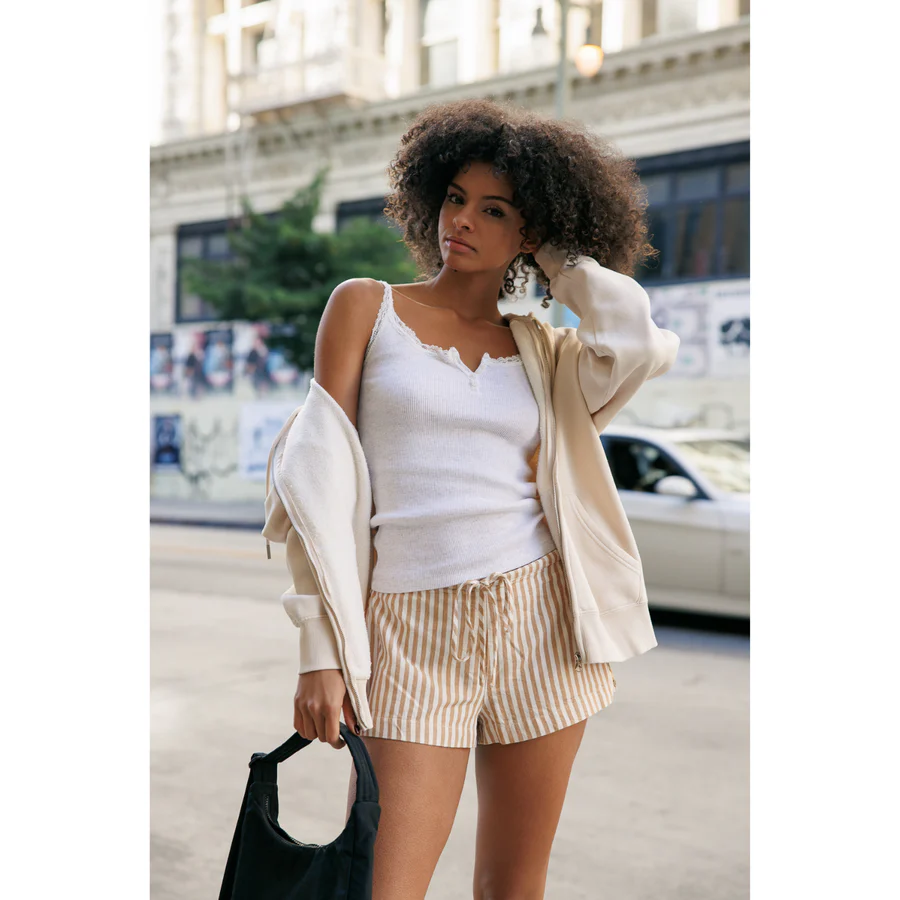 Woman in a cream hoodie and striped shorts