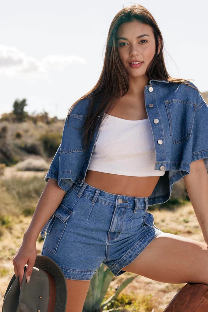 Woman wearing comfy shorts made of denim with a white crop top and denim jacket