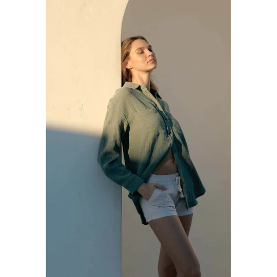 A woman in a green gauze top and white linen shorts