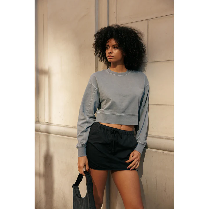 A woman in a grey sweatshirt and black shorts