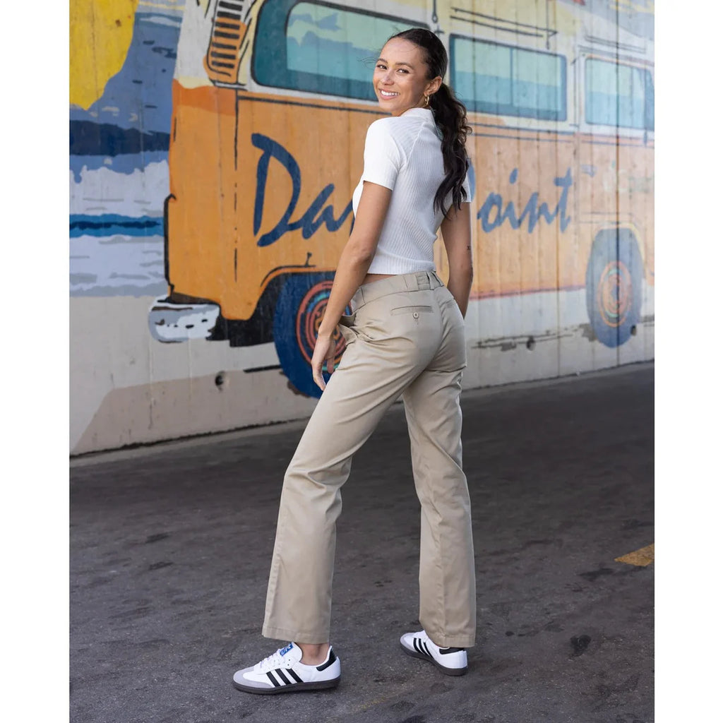 A woman wearing khaki pants in front of a Dana Point mural