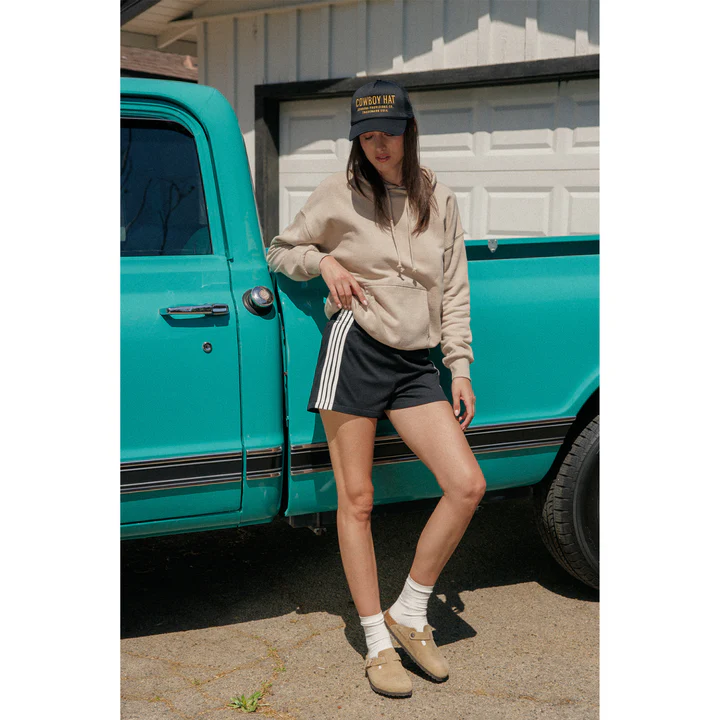 Woman in a light brown hoodie and navy shorts
