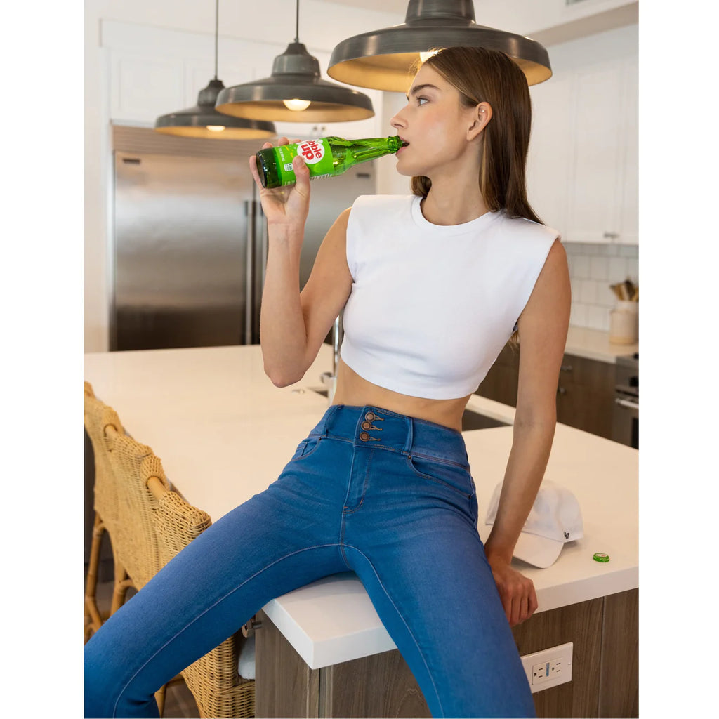 A woman on a kitchen counter wearing skinny, medium-wash knit denim jeans