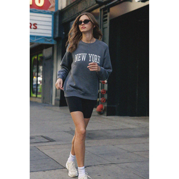 A woman in a New York crewneck sweatshirt
