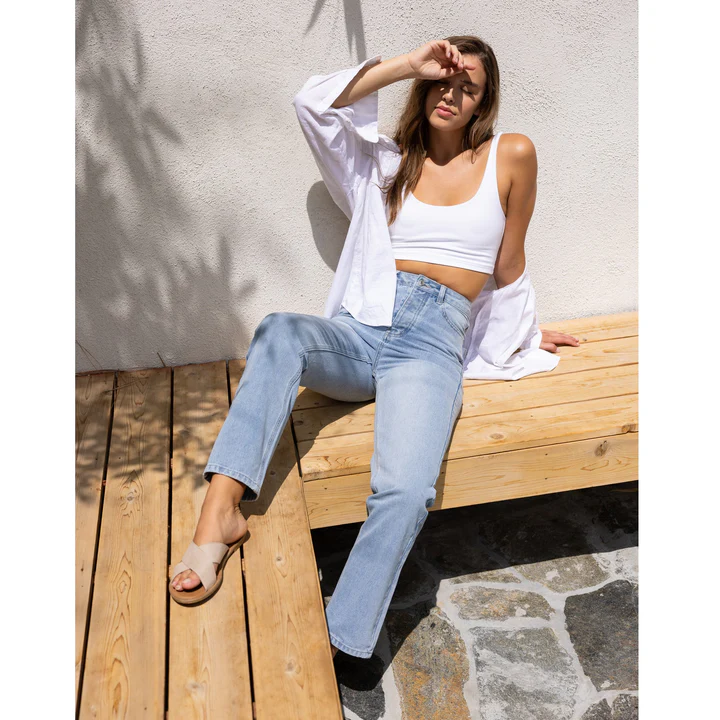 A woman sunbathing while wearing light blue women's high-rise skinny jeans