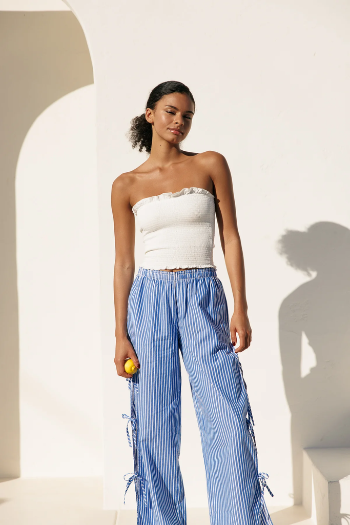 Woman wearing a white tube top and blue striped pants