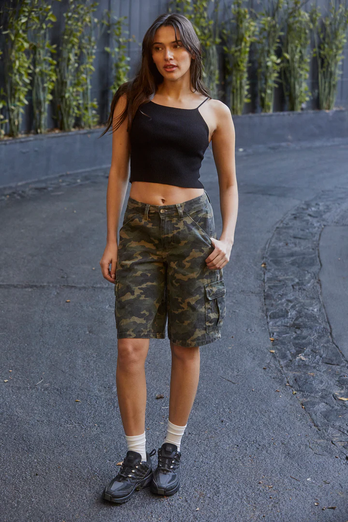 A model wearing women's utility cargo shorts in camo print with a black tank top