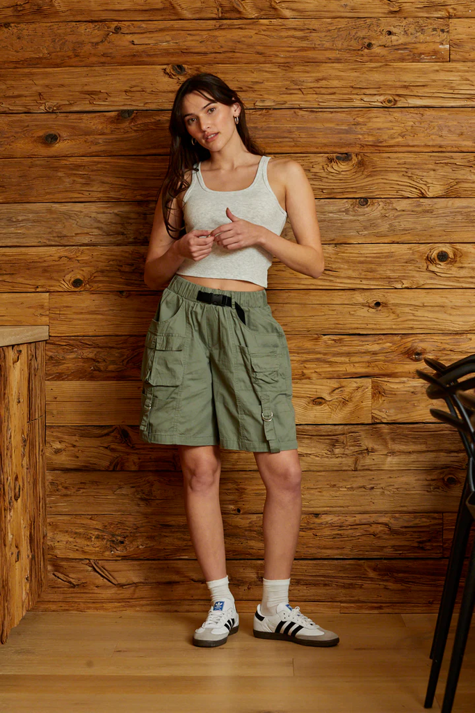 Woman wearing white tank top with olive green women’s baggy cargo shorts